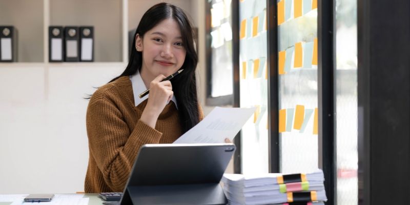 Mulher de negócios asiática usando calculadora e laptop para fazer matemática, finanças em uma mesa de escritório, impostos